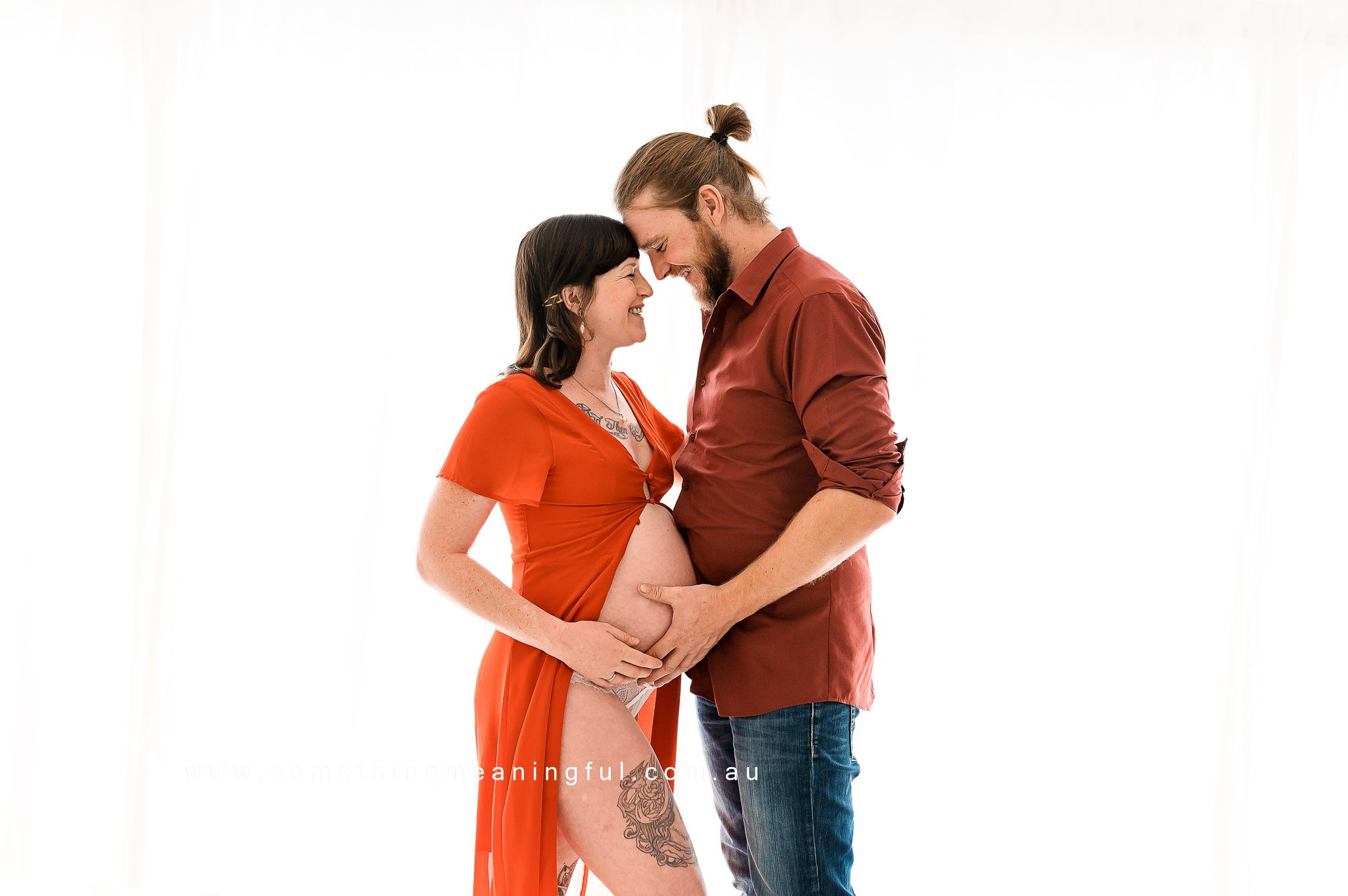 Radiant soon-to-be parents sharing joy and laughter during a cozy studio maternity photography session